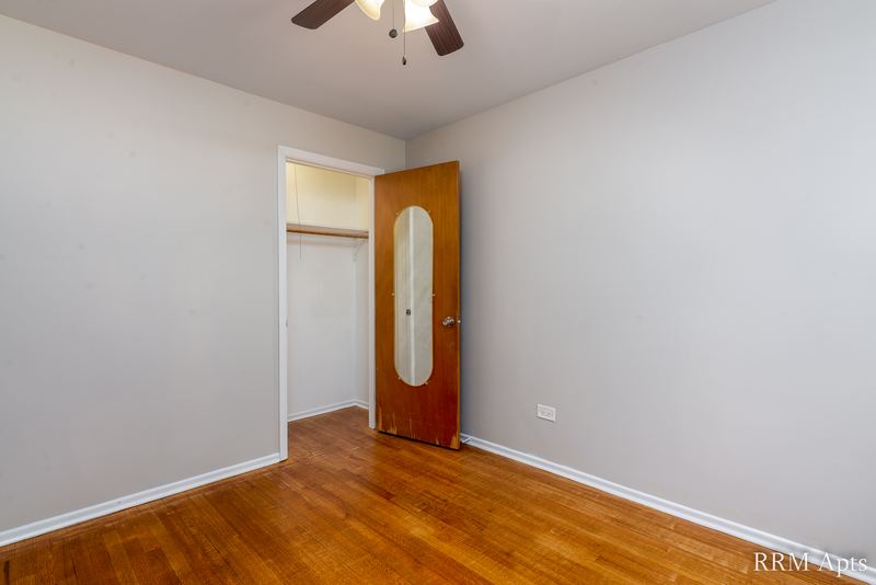 Bedroom with wood floor, ceiling fan, open closet and a wood door with an oval mirror, Westerfield Place apartment 149 A