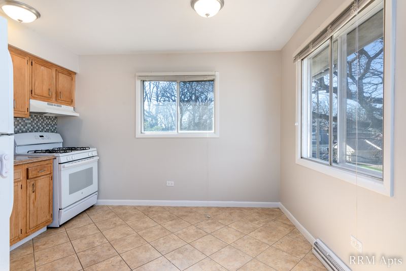 Kitchen with oak cabinets, white gas stove, tile floor and two windows, Westerfield Place apartment 149-C