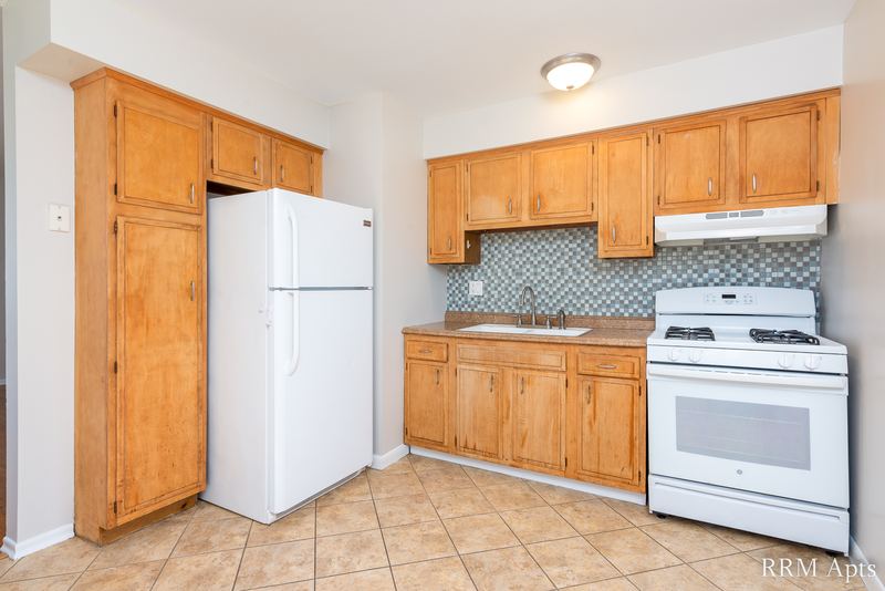 Kitchen with oak cabinets, white refrigerator, white gas stove and tile floor, Westerfield Place apartment 149-C