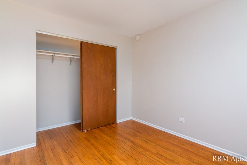 Bedroom with wood floor and an open closet with a wood door, Westerfield Place apartment 149-C