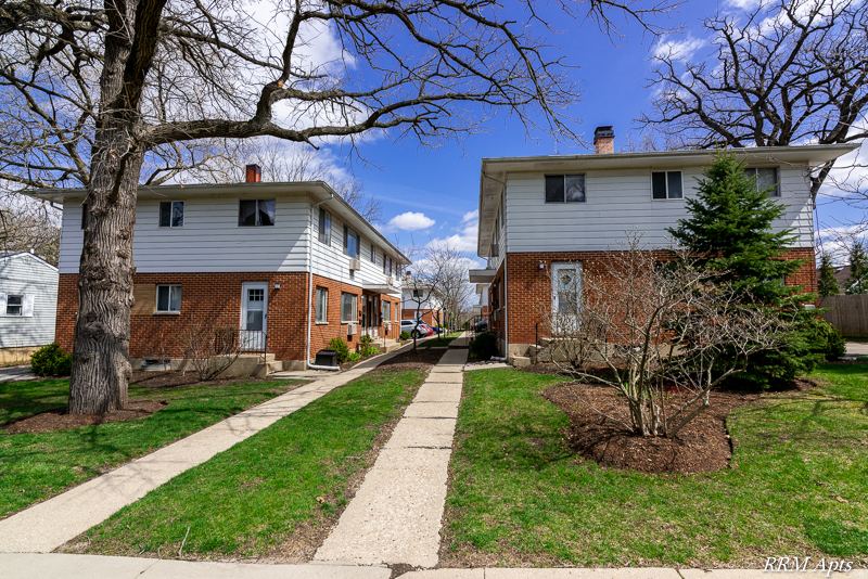 Two-story brick and siding apartment buildings with lawns and a walkway at Westerfield Place, Grayslake